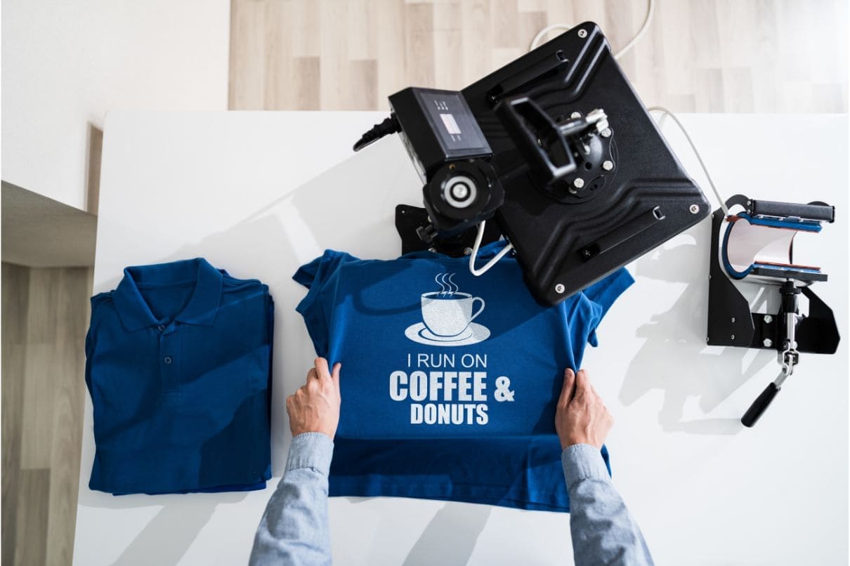 A person holding a blue shirt with a coffee and doughnut design
